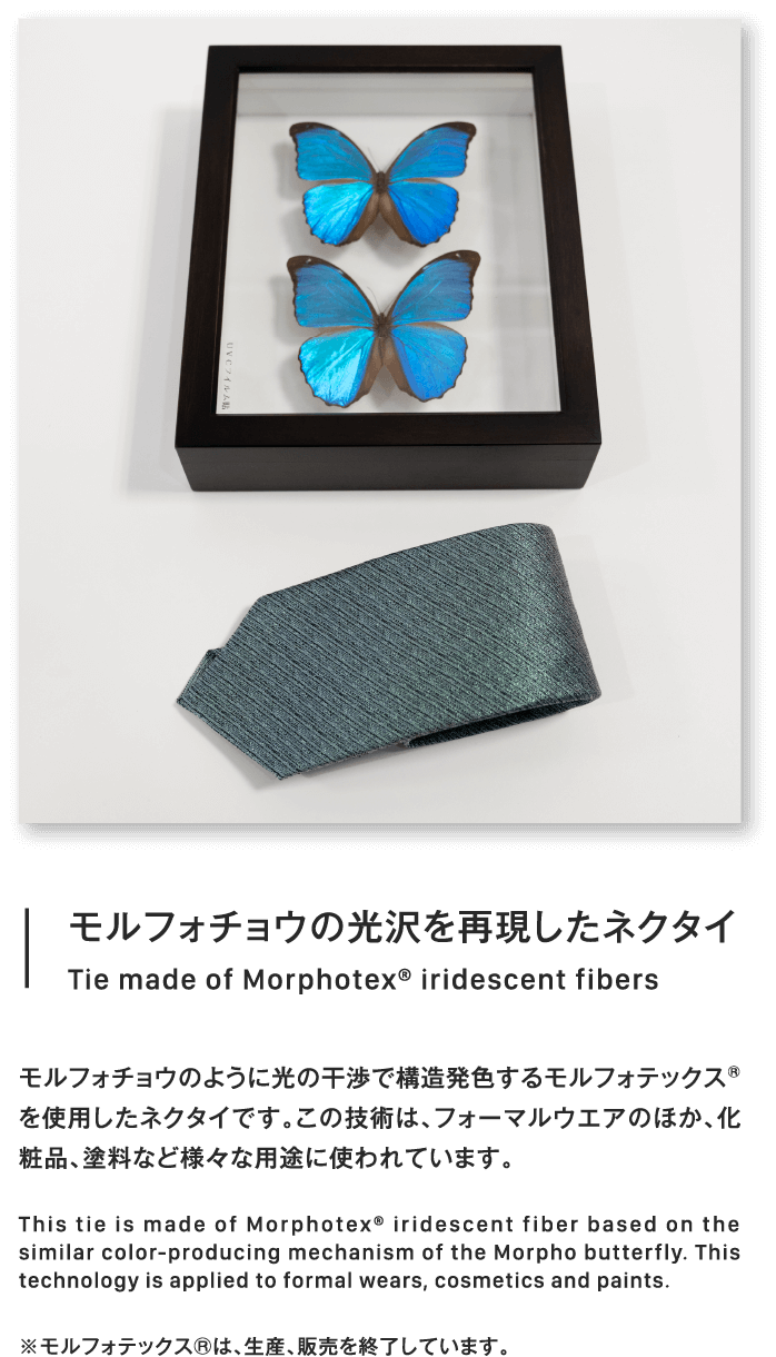 モルフォチョウの光沢を再現したネクタイTie made of Morphotex® iridescent fibersモルフォチョウのように光の干渉で構造発色するモルフォテックス®を使用したネクタイです。この技術は、フォーマルウエアのほか、化粧品、塗料など様々な用途に使われています。This tie is made of Morphotex® iridescent fiber based on the similar color-producing mechanism of the Morpho butterfly. This technology is applied to formal wears, cosmetics and paints.※モルフォテックス®は、生産、販売を終了しています。